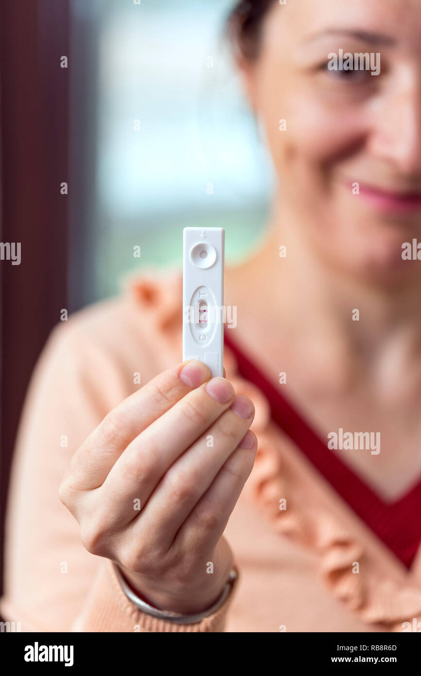 Glückliche junge Frau mit positiven Schwangerschaftstest in der Hand Stockfoto