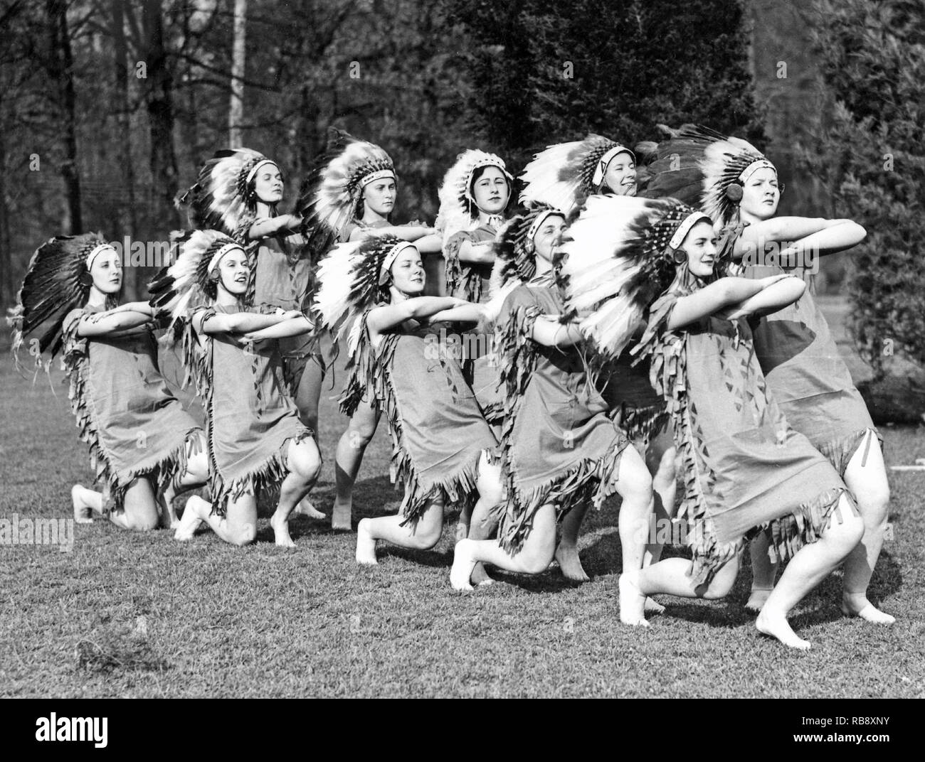 Alle gekleidet in den 1930er Jahren. Eine Gruppe junger Frauen als native american Indianer Federkopfschmuck gekleidet. Stockfoto