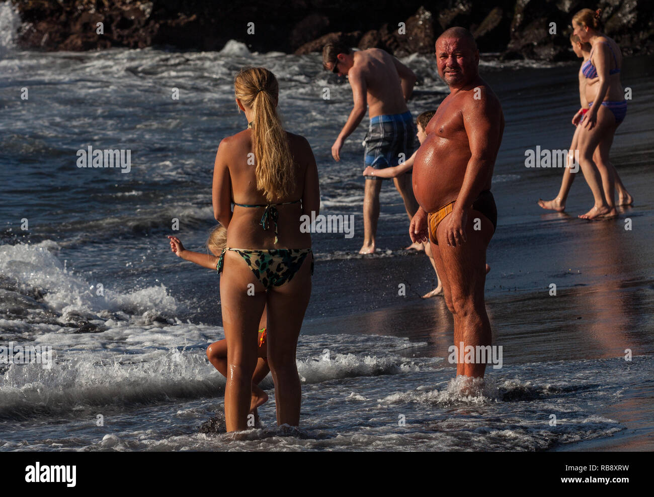 Ein schönes Foto von einem Mann mit einem großen Bauch genießen Sonne am Strand Stockfoto