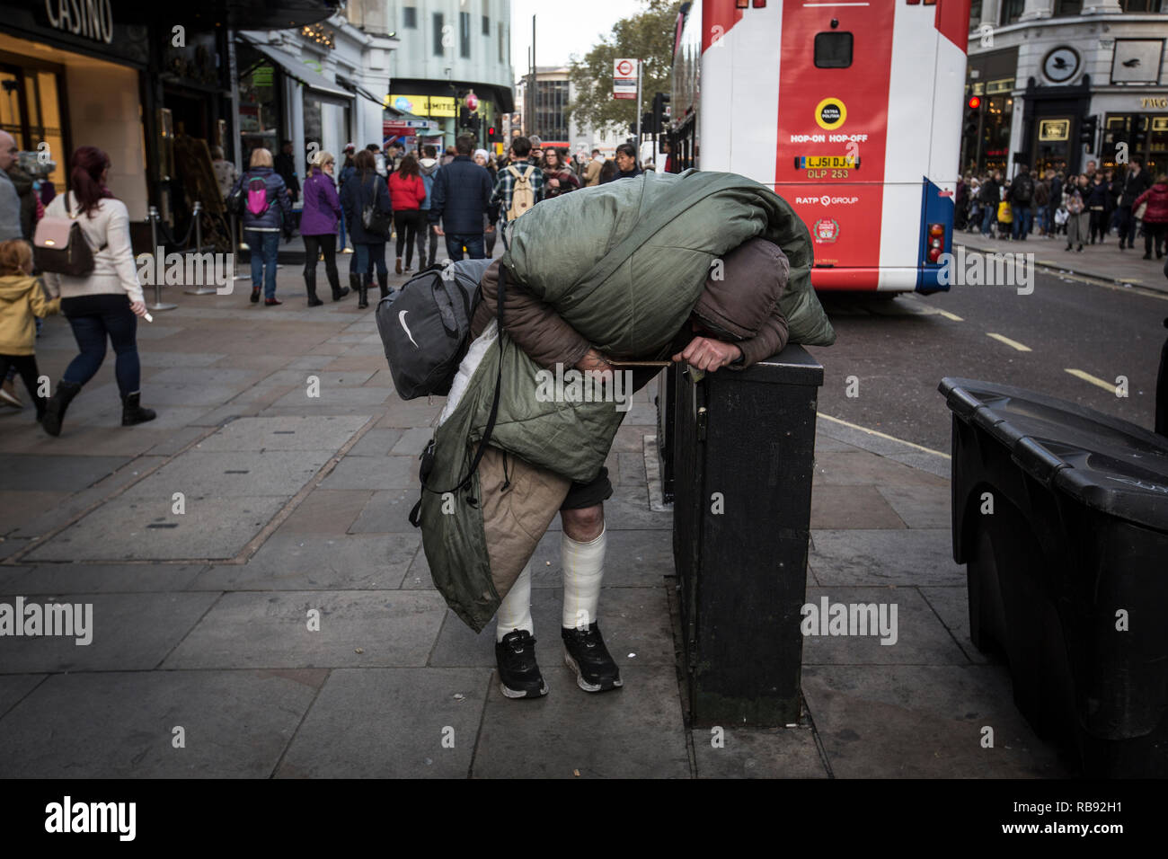Rough sleeper kämpft um seine Sachen zu tragen und auf dem Gehsteig in Trafalgar Square im Zentrum von London, England, Vereinigtes Königreich Stockfoto