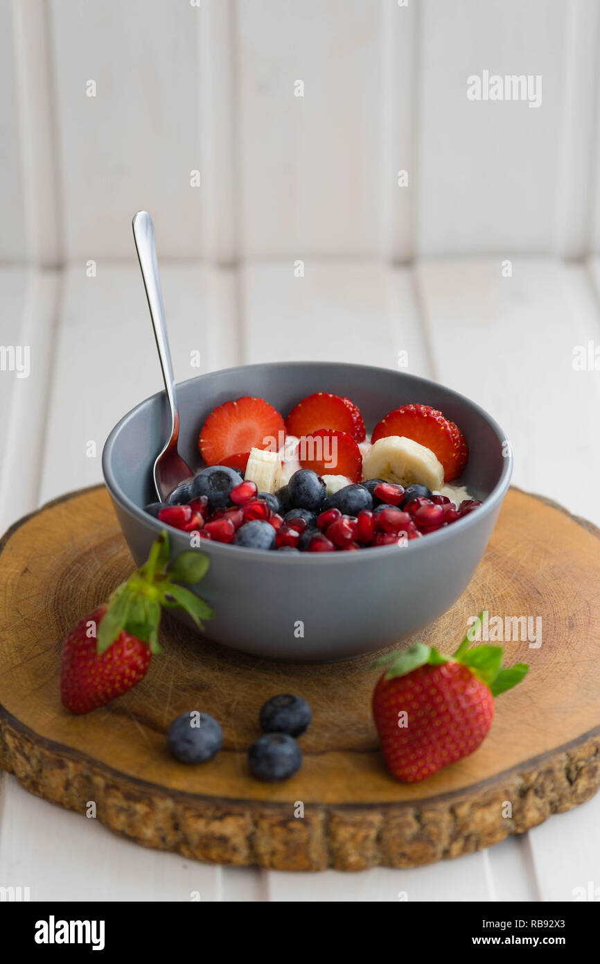 Schüssel mit Joghurt und frischen Früchten wie Erdbeeren, Bananen ...