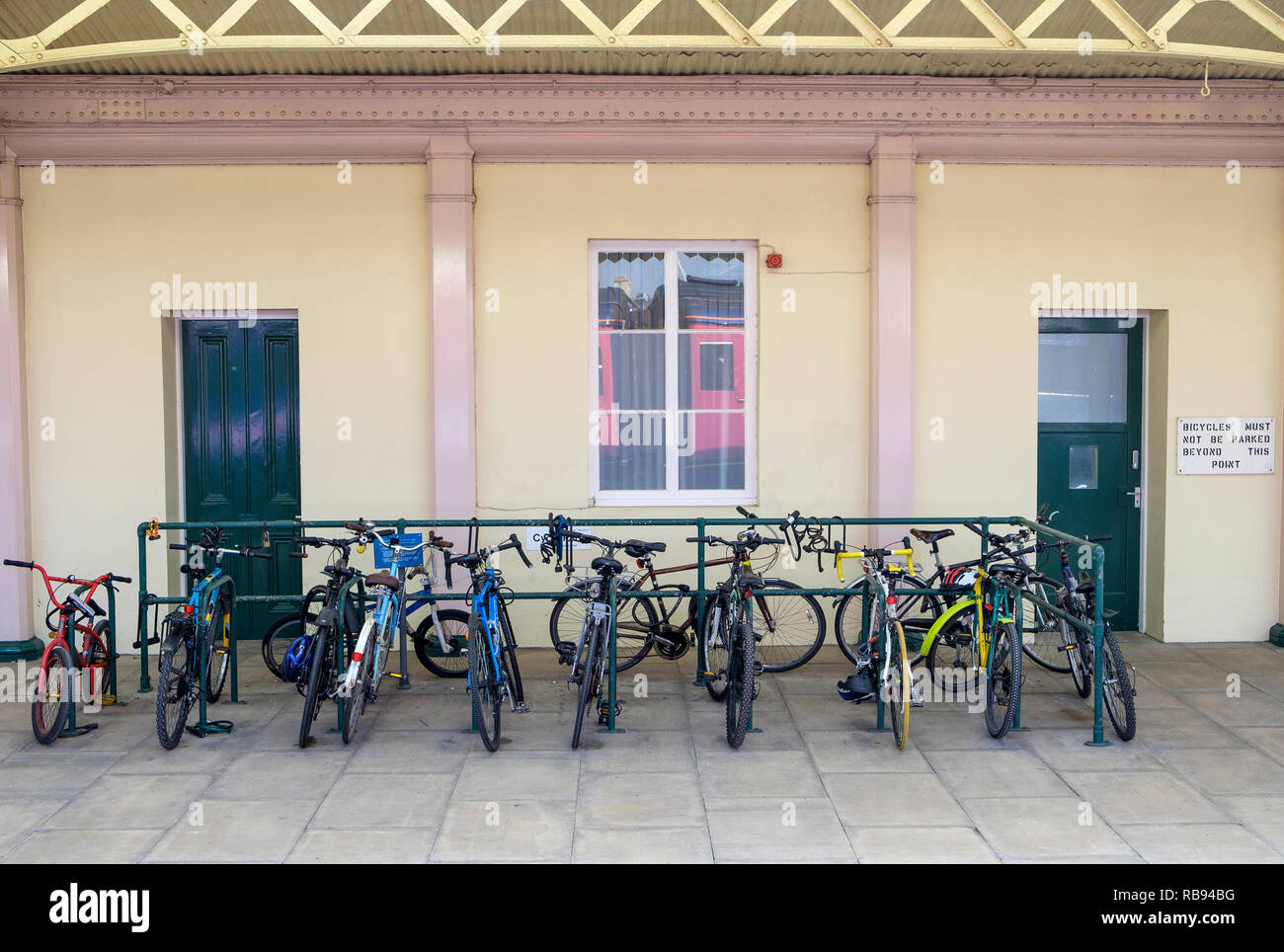 Fahrräder durch Pendler links und in einem fahrradständer sind gesperrt, dargestellt an einem Bahnhof Bahnhof in England, Großbritannien Stockfoto