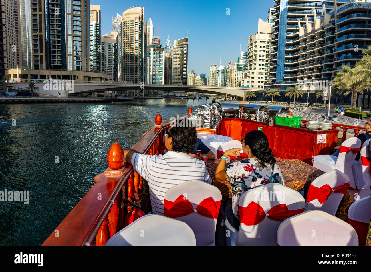Dubai, VAE 11. 10. 2018: die berühmte traditionelle Holz- alten Dhow Cruise tour in der Marina mit Touristen auf dem Board und moderne Wolkenkratzer in der backgou Stockfoto