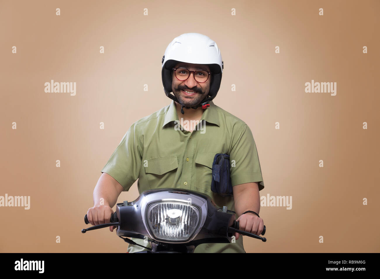Lächelnder Mann mit einer kleinen Tasche in seinen Armen reiten Roller Helm. Stockfoto