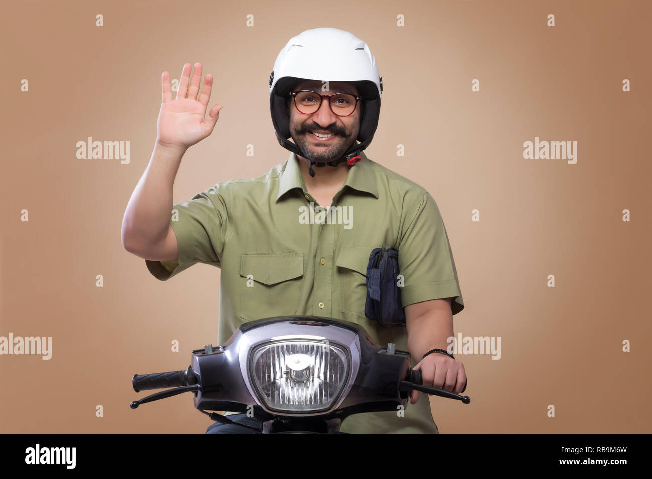 Lächelnder Mann mit einer kleinen Tasche in seinen Armen reiten Roller Helm und Palm. Stockfoto