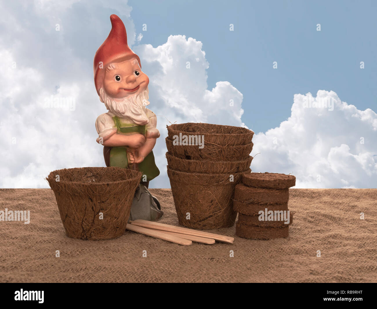 Kokos Blumentöpfe und komprimierte Kompost mit Holz- Etiketten und generische Gartenzwerg. Umweltfreundliche Frühling im Garten arbeiten. Sky zusammengesetzten Hintergrund. Stockfoto