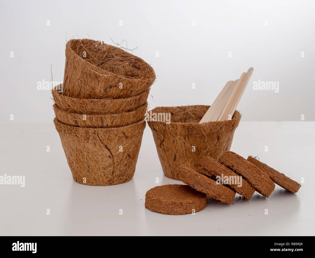 Kokos Blumentöpfe und komprimierte Kompost mit Holz- Etiketten. Umweltfreundliche Frühling im Garten arbeiten. Pale Hintergrund. Stockfoto