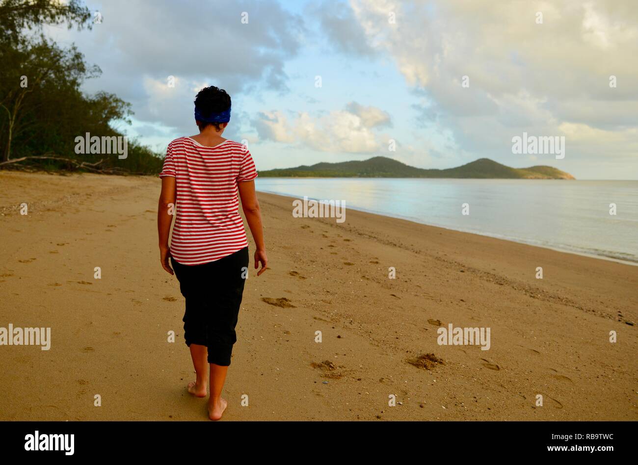 Unabhängige Frau allein auf einem einsamen Strand am frühen Morgen, Smalleys Strand Zeltplatz, Cape Hillsborough National Park, Queensland, Australien Stockfoto