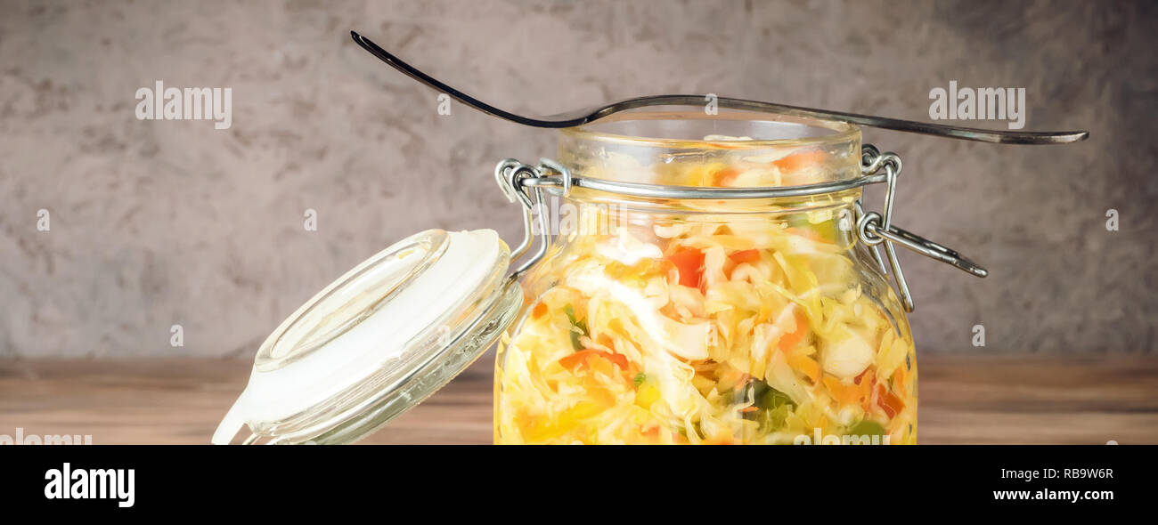 Salat Vorspeise von fermentierten Gemüse Sauerkraut Karotten und Paprika in Glas Glas mit Deckel und Gabel auf rustikalen Holzmöbeln Hintergrund. Konzept trend Diät Stockfoto