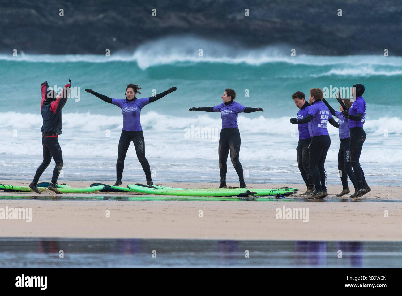 Unerfahrene surfer Erwärmung mit ihrem Ausbilder bis zu Beginn einer surflektion am Fistral Beach in Newquay Cornwall. Stockfoto