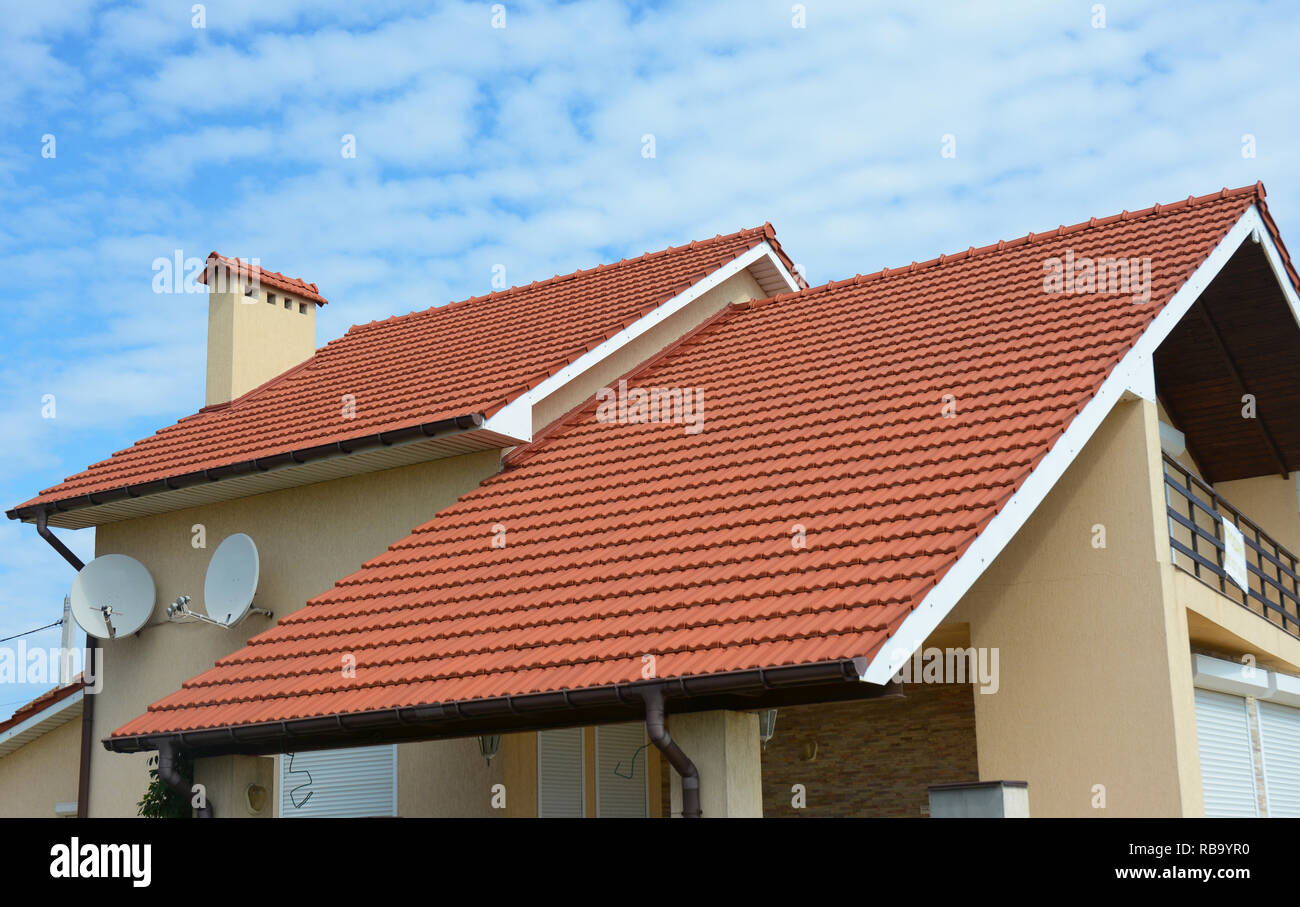 Modernes Haus mit Kamin, roter Ton Ziegeldach und Giebel und Tal Art der Dachkonstruktion. Gebäude im Dachgeschoss Haus Bau mit verschiedenen Arten Stockfoto