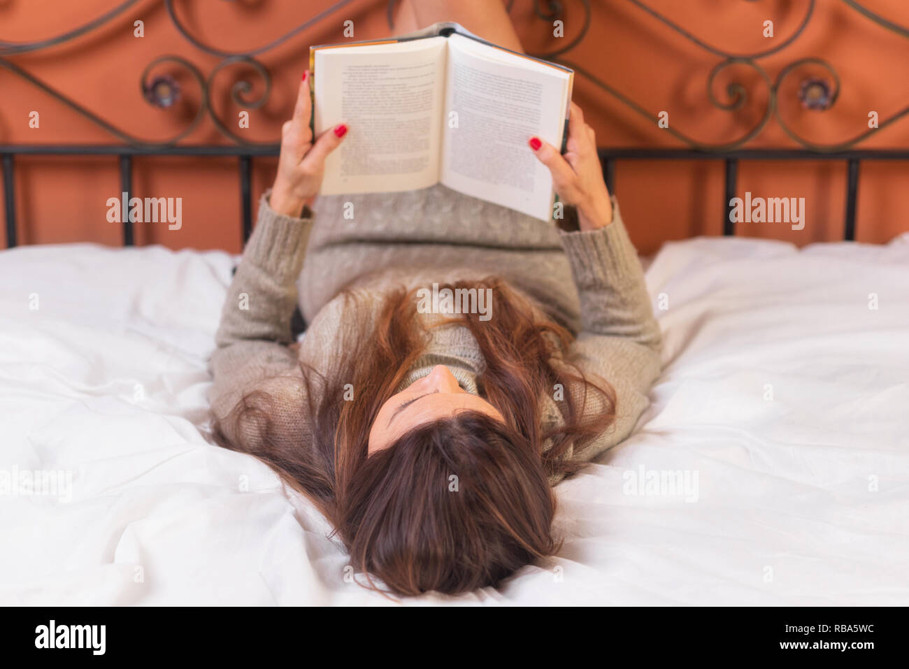 Frau im Bett zu liegen, ein Buch lesen. Stockfoto