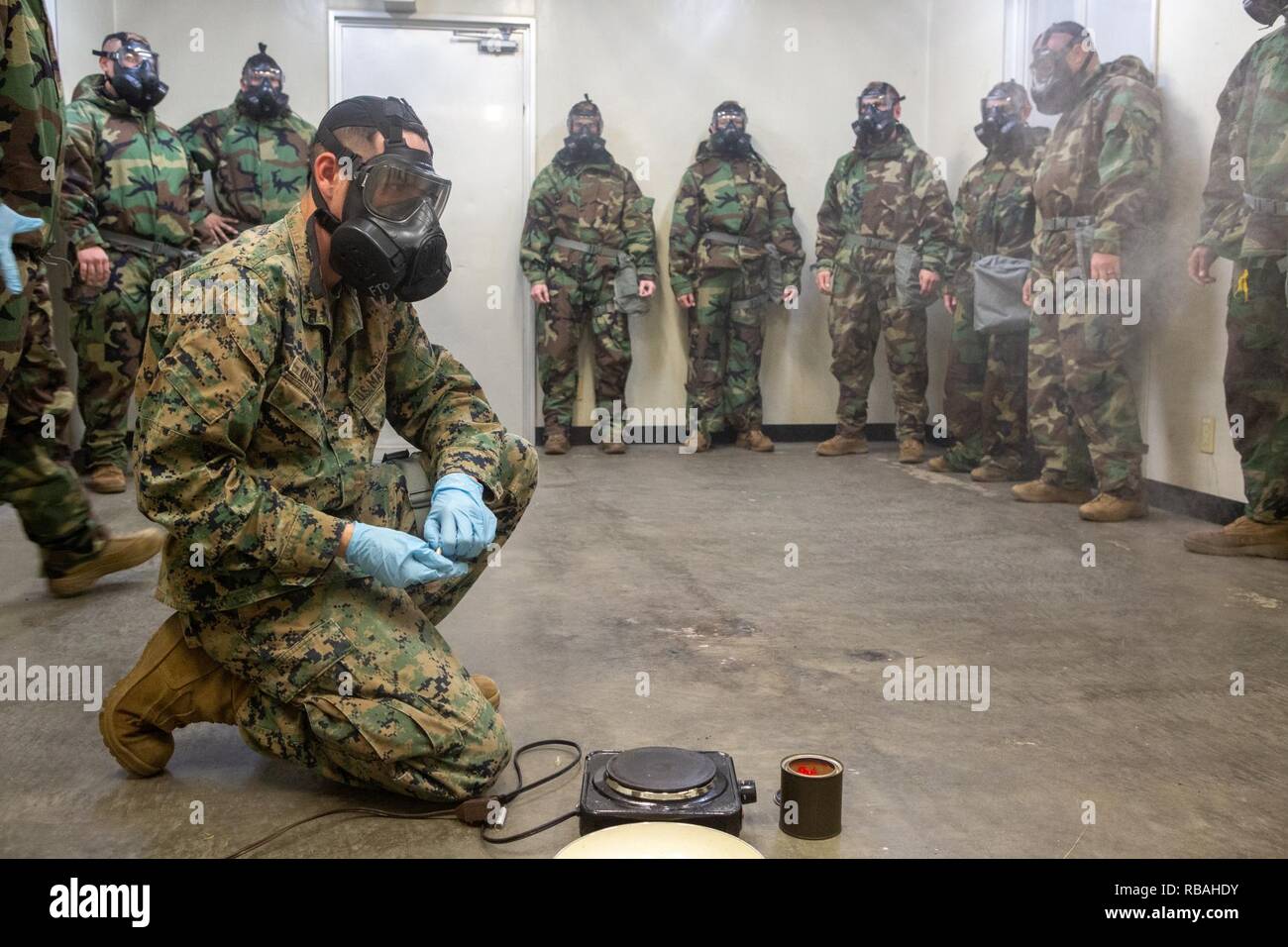 Us Marine Lance Cpl. Michael Oustayan Pausen Kapseln über eine Kochplatte, die Schmelzen und Releases 2-chlorobenzalmalononitrile Gas während für eine Gaskammer Qualifikation im Camp Hansen, Okinawa, Japan, Dez. 19, 2018. Marines sind verpflichtet, ihre Kenntnisse im Umgang mit einem M50-Service Allgemeine Maske durch Brechen des Siegels, die CS-Gas die Maske zu füllen, um zu zeigen, dann Ihre Maske heraus zu löschen. Oustayan ist eine Chemische, biologische, radiologische, nukleare Verteidigung Spezialist mit 7 Kommunikation Bataillon, III Marine Expeditionary Force Information Group. Stockfoto