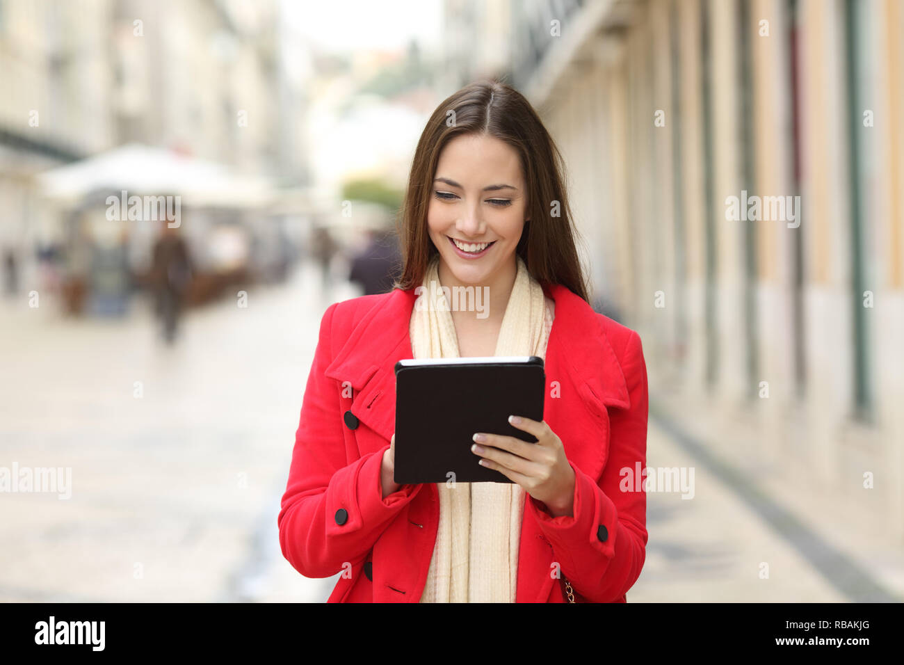 Vorderansicht Portrait Of Happy coman Kontrolle Tablette Inhalt zu Fuß auf der Straße Stockfoto