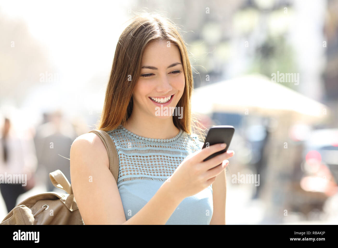 Glückliches Mädchen zu Fuß auf der Straße prüfen smart phone Inhalt Stockfoto