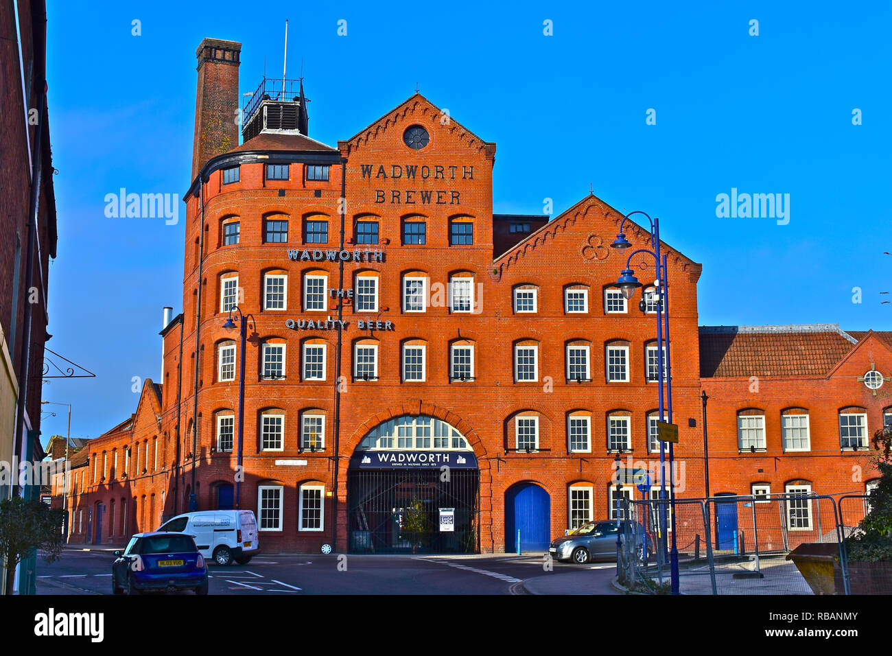 Blick auf die Straße des berühmten devizes Brauerei Wadworth & belegten Gebäude von 1875 gegründet. Markanten roten Backsteinmauern gegen einen klaren blauen Himmel. Stockfoto