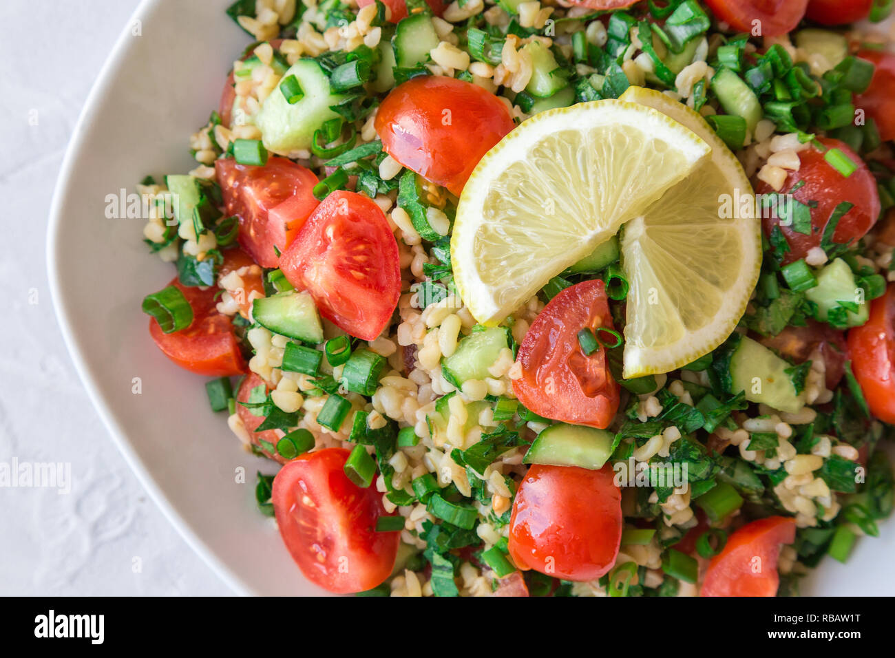 Tabbouleh (Tabouli) Salat auf einem Teller auf hellen Hintergrund. Gesunde vegetarische Nahrung. Libanesische Küche. Ansicht von oben. Stockfoto