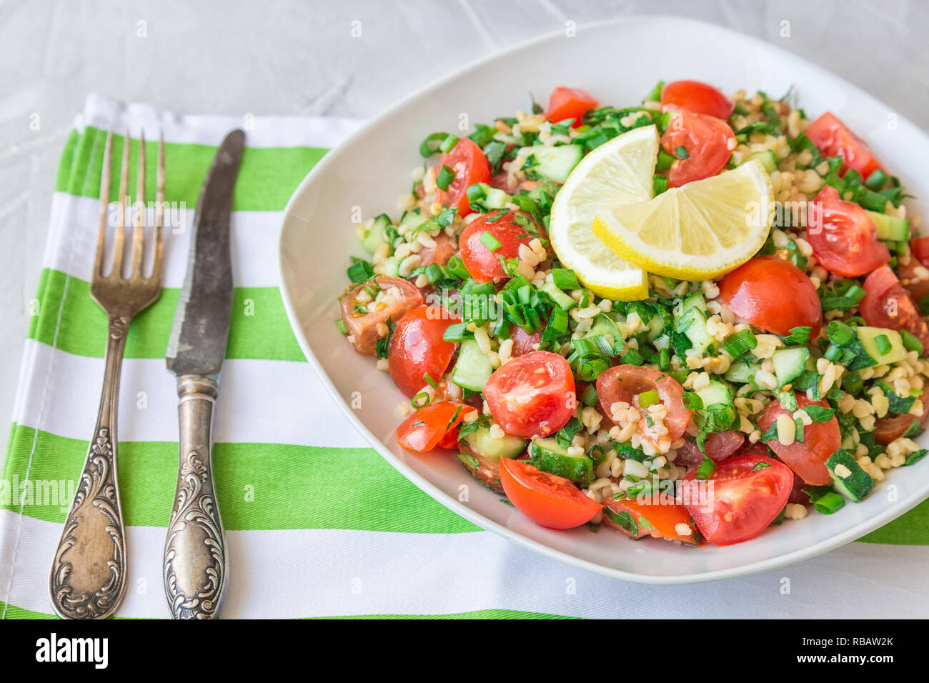 Tabbouleh (Tabouli) Salat auf einem Teller auf Hellgrau konkreten Hintergrund. Gesunde vegetarische Nahrung. Libanesische Küche Stockfoto