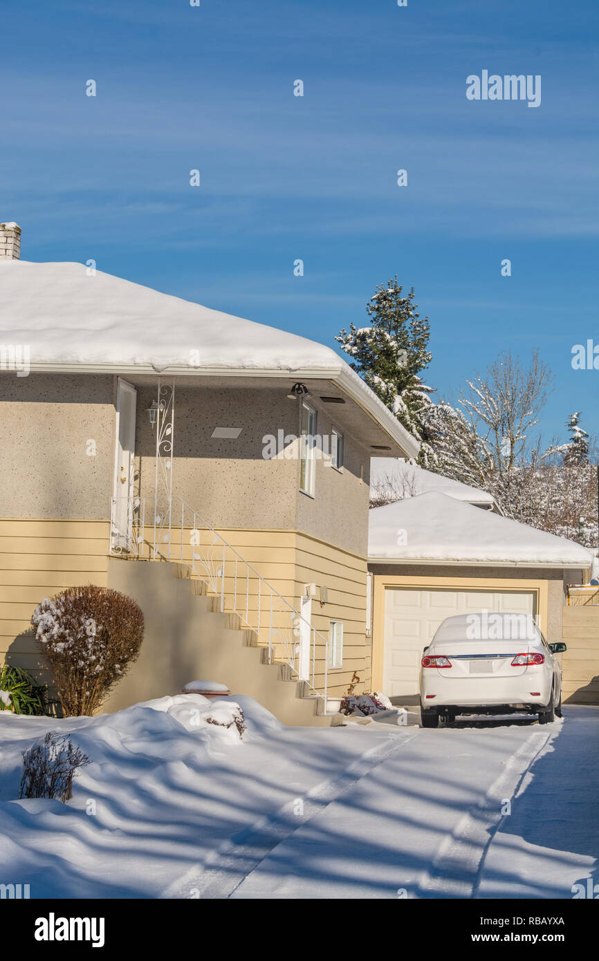 Schnee bedeckt Wohn- Einfahrt mit weißen Auto geparkt ist Stockfoto