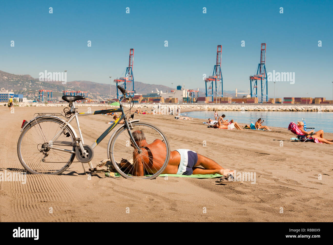 Ein Mann mit dem Fahrrad auf den Strand der Stadt in Malaga - Spanien Stockfoto