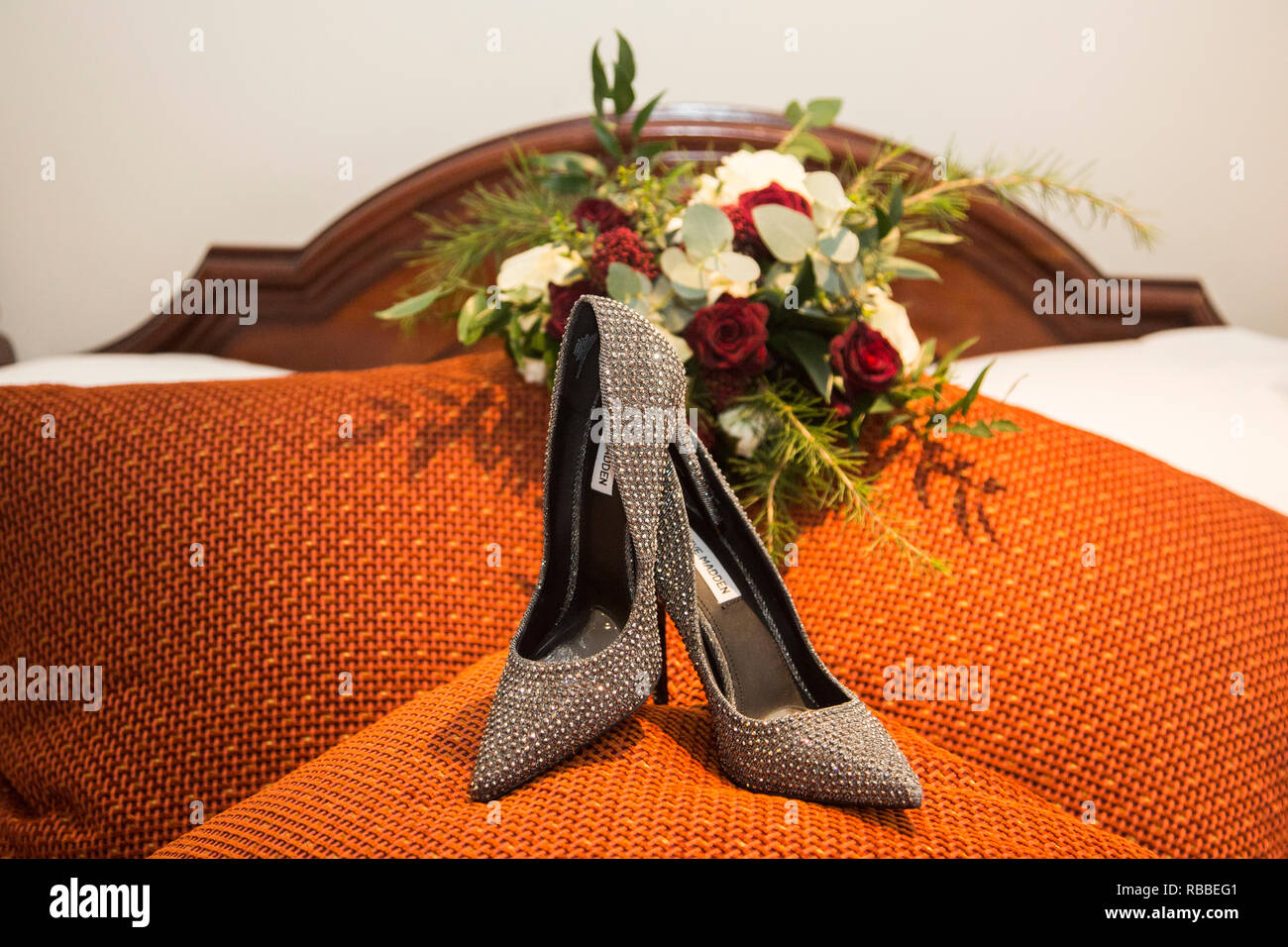 Bräute Hochzeit Tag Schuhe mit hohen Absätzen, mit Ihrem Blumenstrauß im Hintergrund die Schuhe sind Schwarz und Silber glitzernd High Heels. Stockfoto