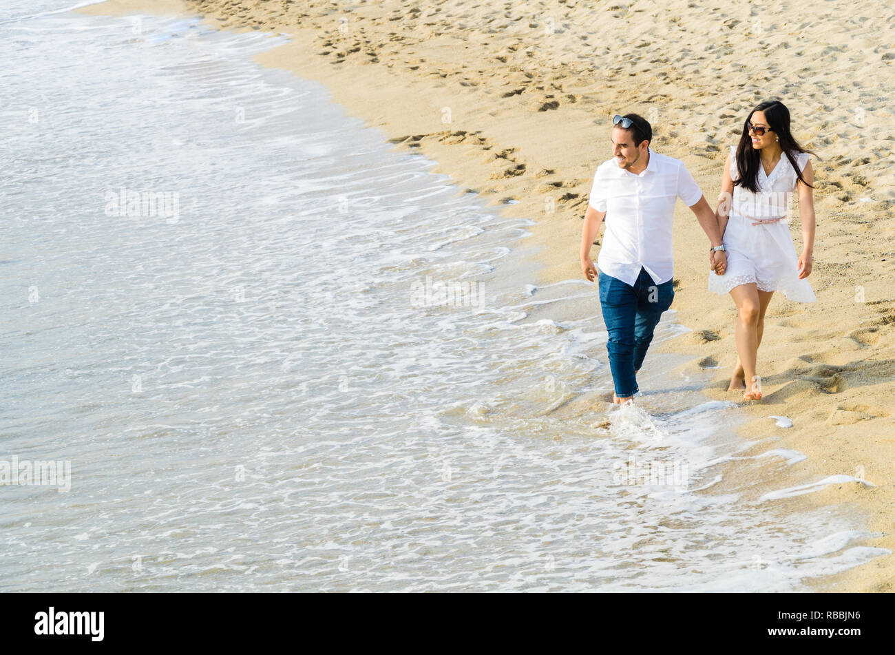 Barfuß junges Paar hand in hand am Strand am Rande des Surf, da Sie einen erholsamen Tag am Meer auf Ihren Sommer Urlaub verbringen. Stockfoto