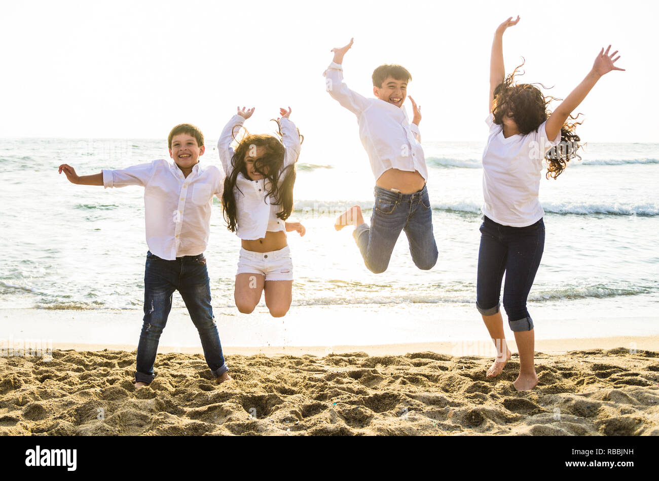 Happy Kids zusammen Springen mit Sonnenlicht am Strand Stockfoto