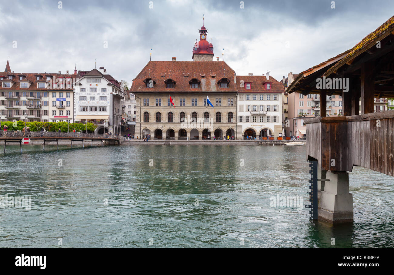 Luzern, Schweiz - 7. Mai 2017: Stadtbild der Stadt Luzern mit Rathaus und hölzerne Brücke über die Reuss. Gewöhnliche Menschen zu Fuß der Böschung Stockfoto