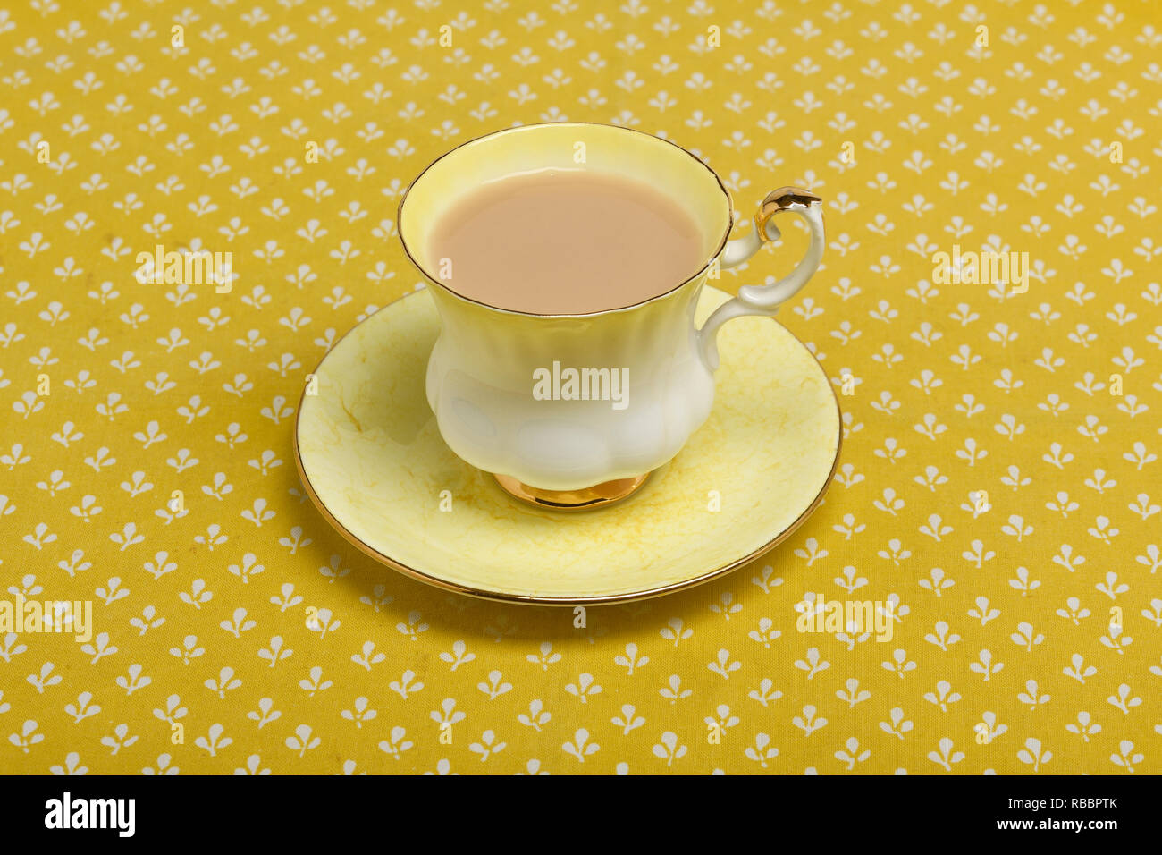 Kaffee in einem gelben bone china Tasse und Untertasse auf eine gelbe Tischdecke Stockfoto