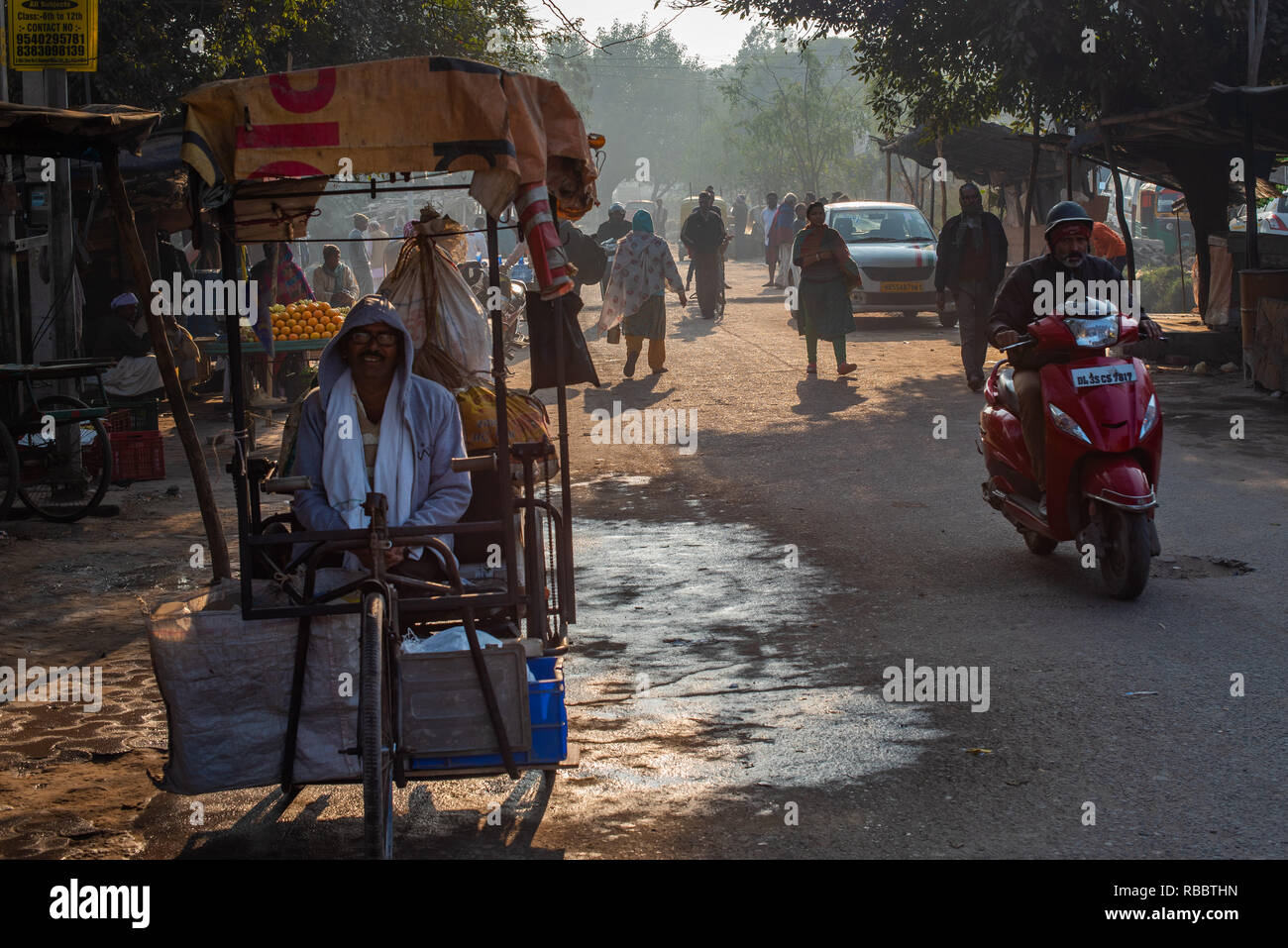 Eine Rikscha - rikscha - wala (Mann) wartet auf Passagiere in diesem Morgen Szene in JJ Kolonie Madanpur Khadar, New Delhi während Pendler Vergangenheit rush. Stockfoto