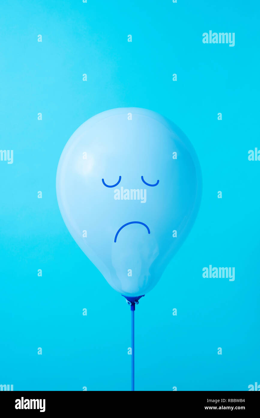 Nahaufnahme von einem blauen Ballon mit einem traurigen Gesicht in es gezeichnet, auf einem blauen Hintergrund, mit einigen leeren Raum auf der Oberseite Stockfoto