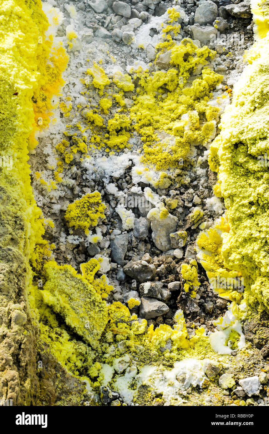 Gelbe Schwefelkristalle auf Felsen von einem Vulkan Krater auf der Insel Vulcano, Äolischen Inseln, Sizilien. Gas, Dampf und Rauch aus fumarole Stockfoto