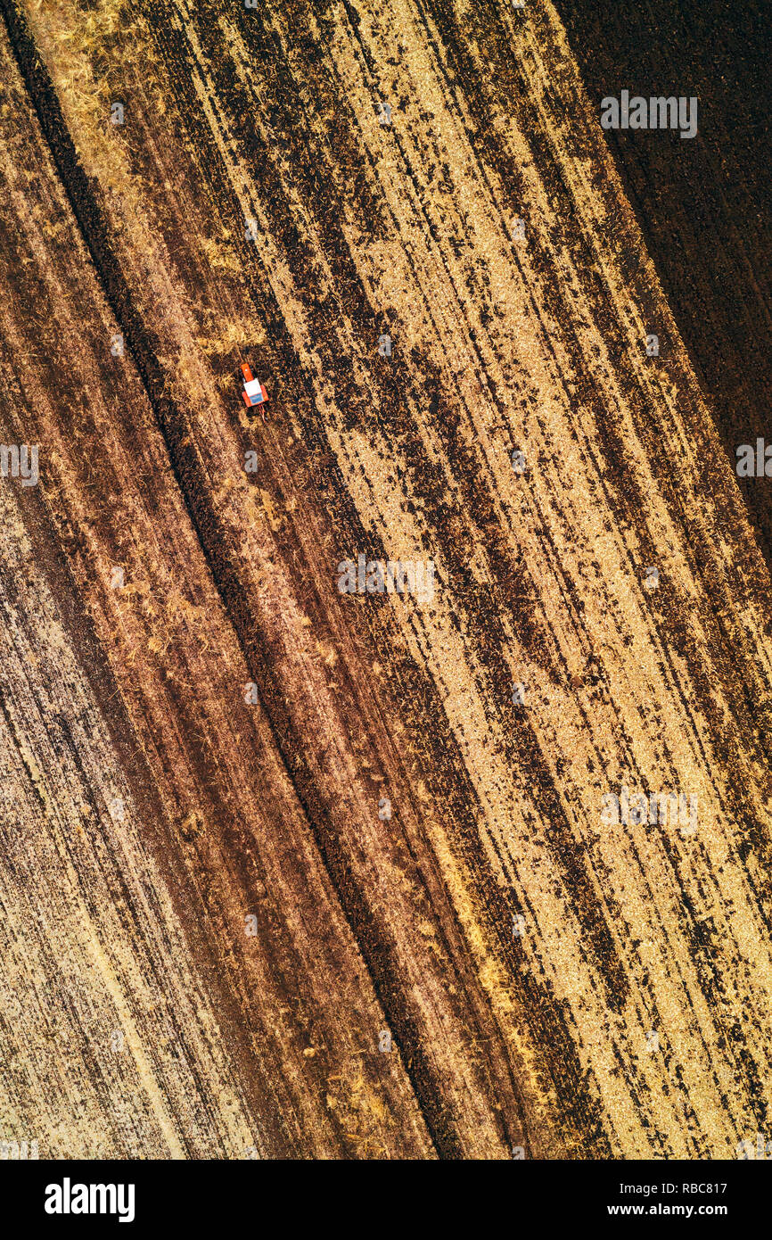 Luftaufnahme von landwirtschaftlichen Traktor pflügen Feld in kalten Herbst Nachmittag von Drone pov Stockfoto