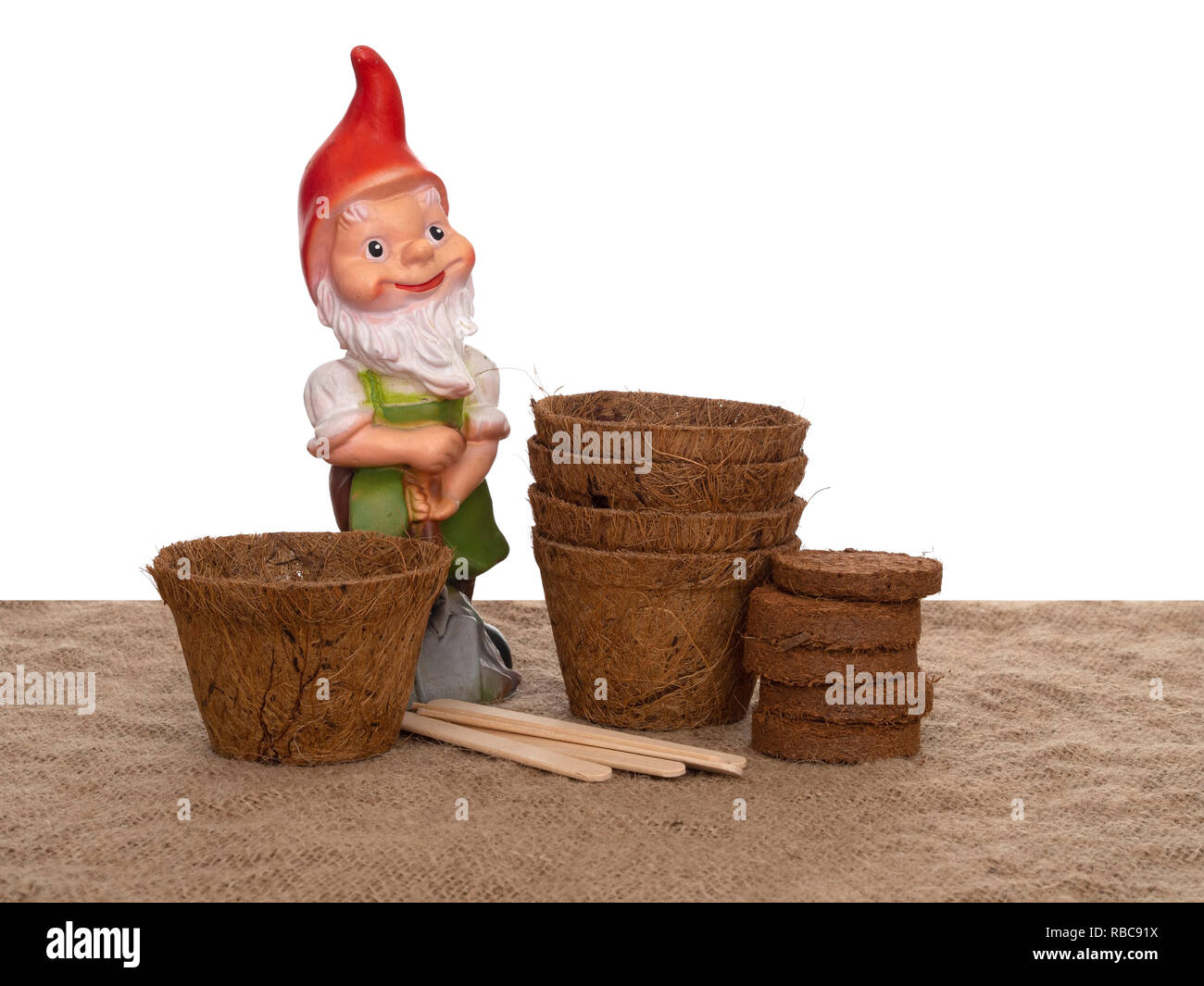 Kokos Blumentöpfe und komprimierte Kompost mit Holz- Etiketten und generische Gartenzwerg. Umweltfreundliche Frühling im Garten arbeiten. Auf weissem Hintergrund. Stockfoto