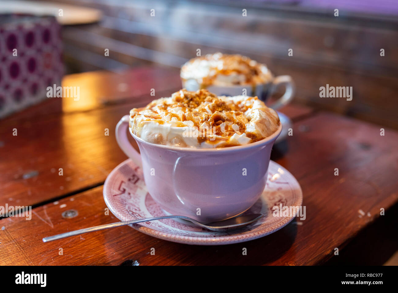 Zwei Tassen frischen Heiße Schokolade mit Sahne und gesalzen Karamell auf braunem Holz- Tabelle. Stockfoto