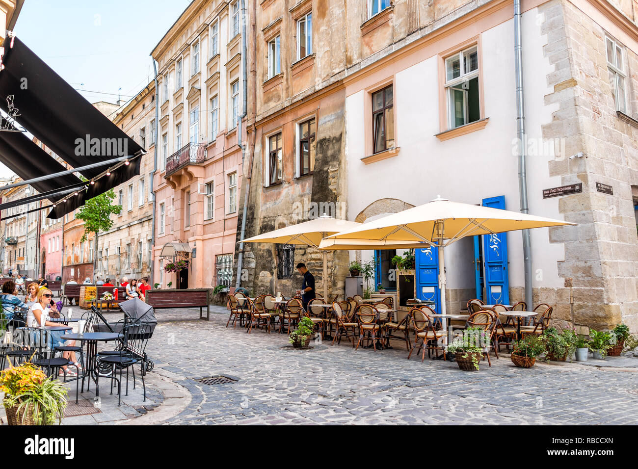 Lemberg, Ukraine - Juli 30, 2018: Straße im historischen Ukrainischen polnischen Lvov Stadt bei Tag mit gelben alten Vintage Gebäude in der Altstadt und Cafe Tabellen Stockfoto