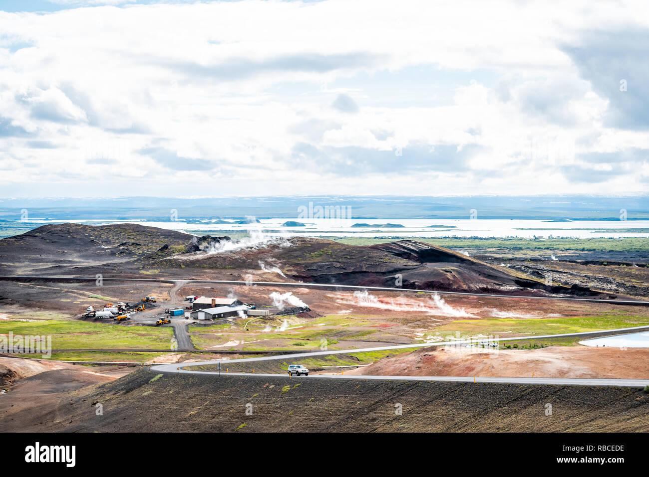 Reykjahlid, Island - 16. Juni 2018: Landschaft hohe Betrachtungswinkel des Sees Myvatn und Fumarolen Dampföffnungen bei bewölkten Tag und Auto auf der Straße Autobahn Stockfoto