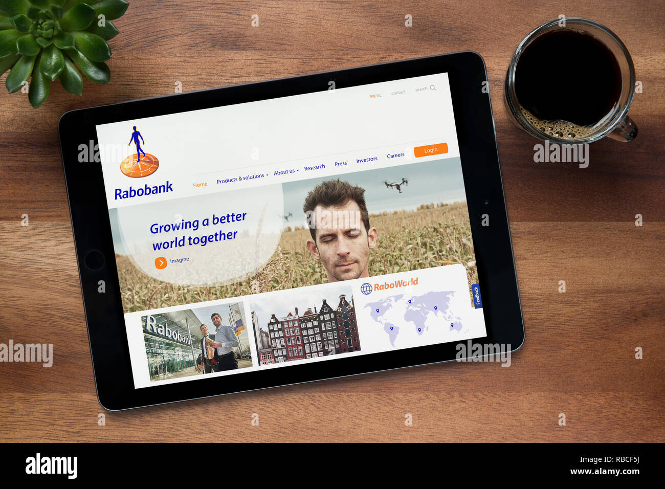 Die Website von Rabobank ist auf einem iPad Tablet gesehen, auf einer hölzernen Tisch zusammen mit einem Espresso und einem Haus Anlage (nur redaktionelle Nutzung). Stockfoto