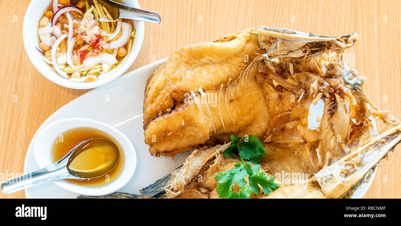 Frittierte Wolfsbarsch mit süßen Fischsauce Essen mit Spice mango Salat auf Holz- Hintergrund, Thai Küche groumet Fruchtart für Website Banner Stockfoto