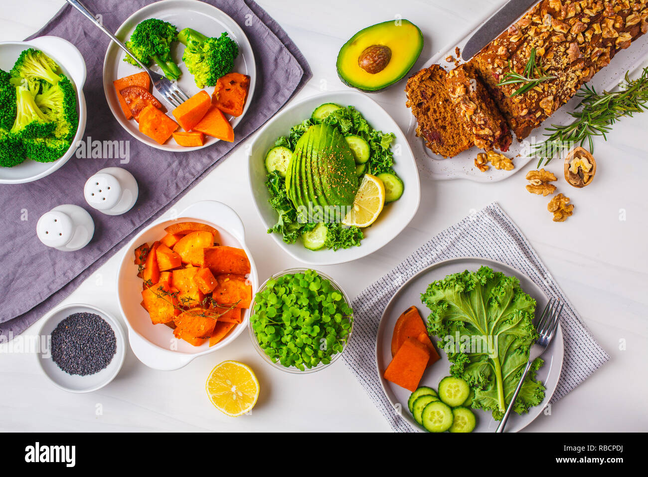 Gesund vegan Food Lunch, Ansicht von oben. Vegetarisches Abendessen Tabelle, Salat, Süßkartoffel, veganen Kuchen, Gemüse auf einem weißen Hintergrund. Stockfoto