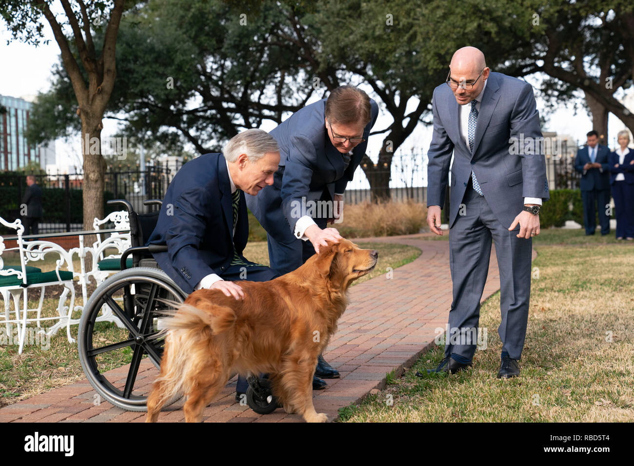 Texas Führer reg. Greg Abbott (im Stuhl), Leutnant. Dan Patrick, und Sprecher des Repräsentantenhauses Dennis Bonnen grüße Abbott's Golden Retriever, Pfannkuchen, außerhalb des Governor's Mansion in Austin nach einer Pressekonferenz zu Beginn der 86. Legislaturperiode. Stockfoto