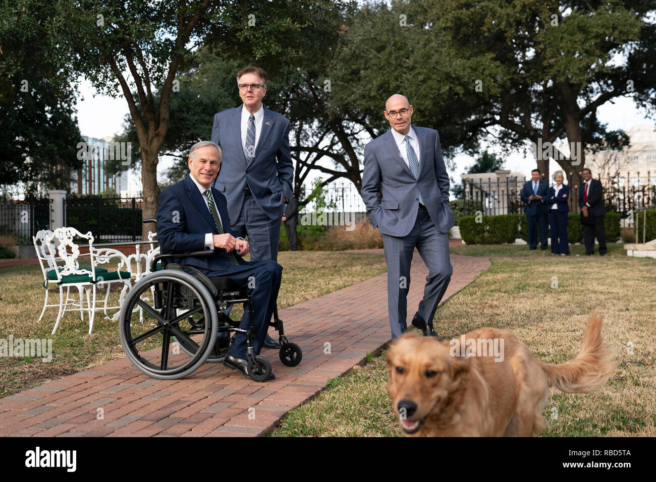 Texas Führer reg. Greg Abbott (im Stuhl), Leutnant. Dan Patrick, und Sprecher des Repräsentantenhauses Dennis Bonnen grüße Abbott's Golden Retriever, Pfannkuchen, außerhalb des Governor's Mansion in Austin nach einer Pressekonferenz zu Beginn der 86. Legislaturperiode. Stockfoto