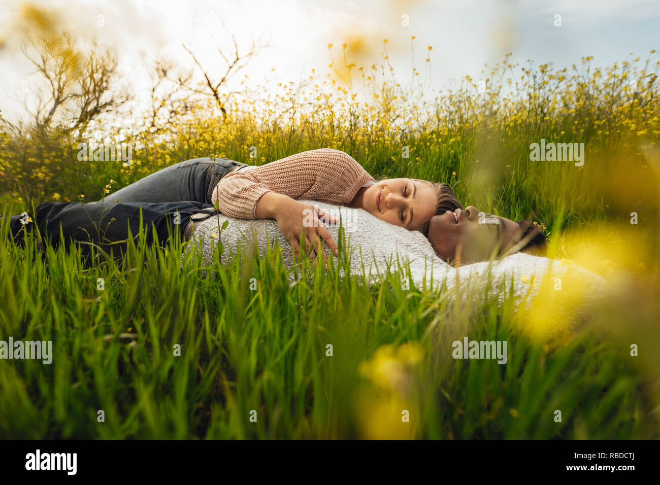 Junge Paare, die auf dem Gras in der Wiese. Entspannt junger Mann und eine Frau, die auf dem Gras im Freien. Stockfoto