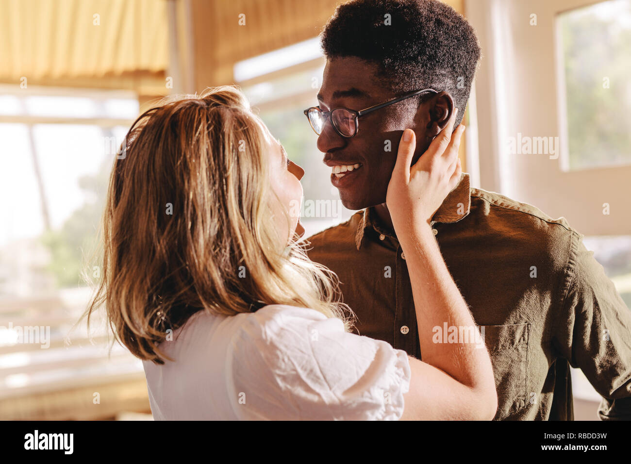Schöne interracial Paare suchen einander mit der Liebe beim Stehen im Innenbereich. Romantischer Mann und Frau einander umarmen. Stockfoto