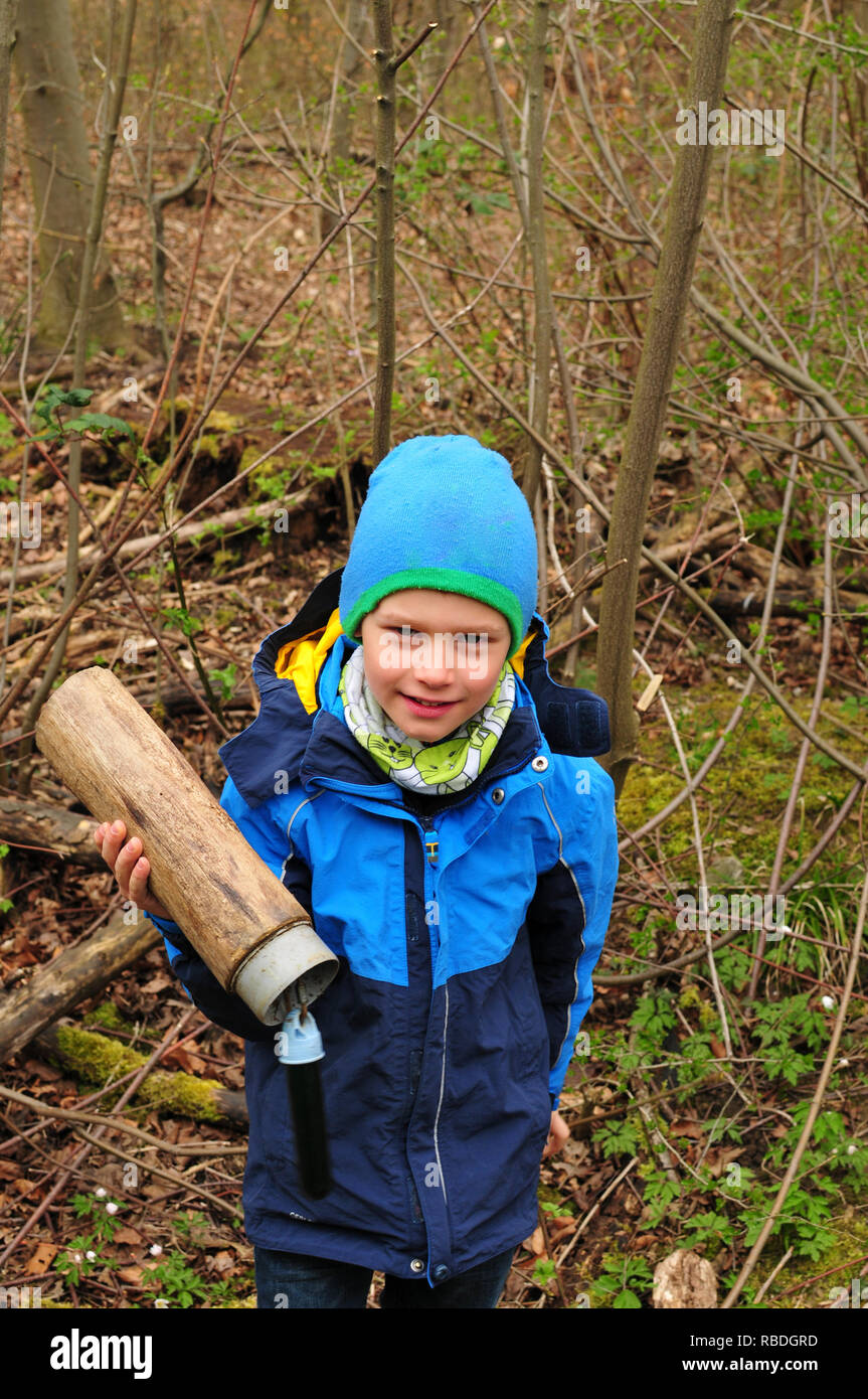 Geocaching Junge findet einen gut getarnten Cache im Wald Stockfoto