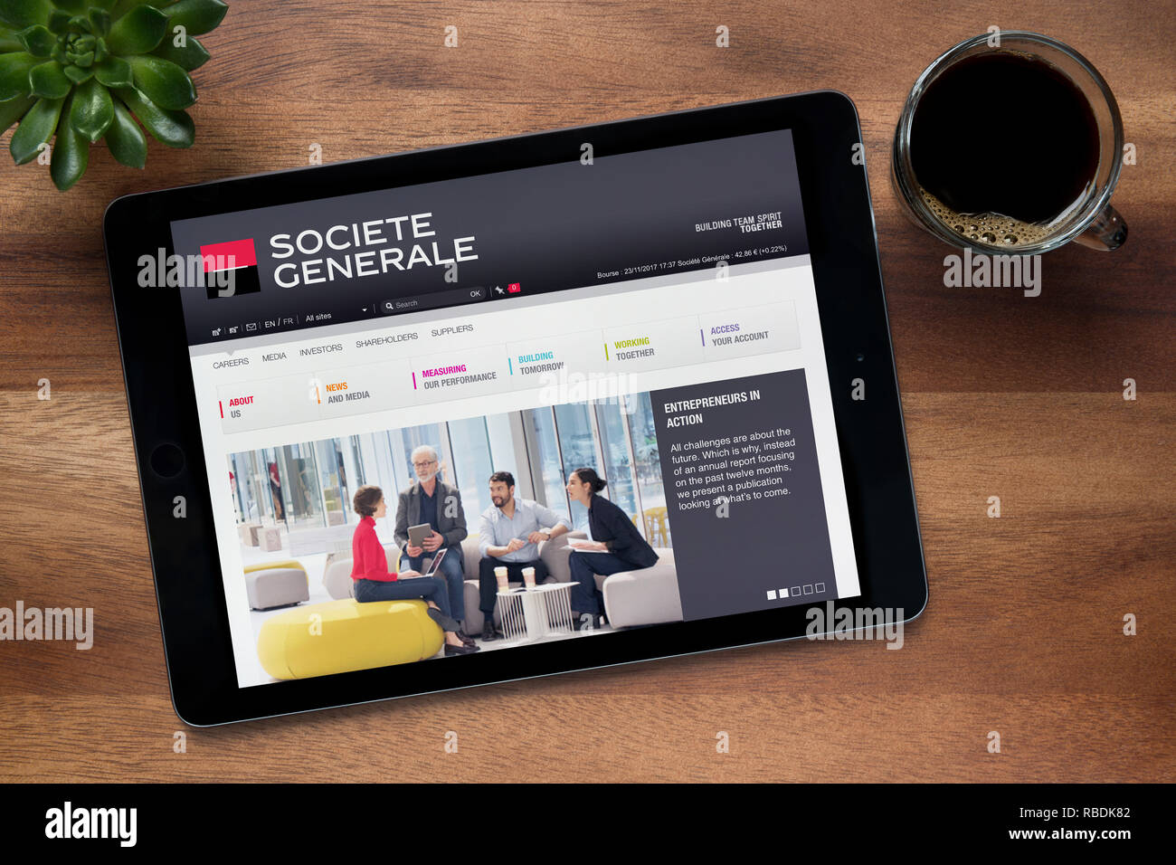 Die Website von Societe Generale ist auf einem iPad Tablet gesehen, auf einer hölzernen Tisch zusammen mit einem Espresso und einem Haus Anlage (nur redaktionelle Nutzung). Stockfoto