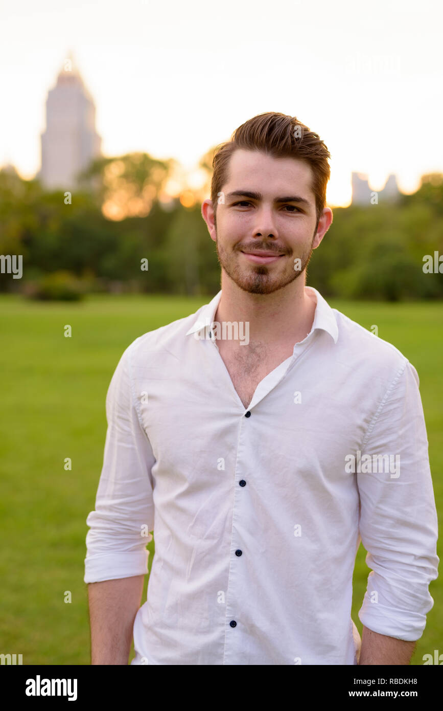 Porträt der jungen gutaussehenden Mann im Park lächelnd Stockfoto