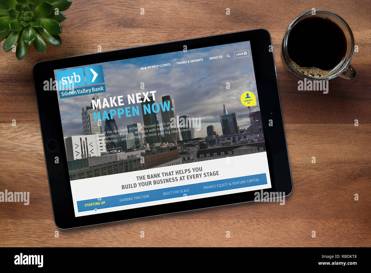 (Die Website der SVB Silicon Valley Bank) ist auf einem iPad Tablet gesehen, auf einer hölzernen Tisch zusammen mit einem Espresso und einem Haus Anlage (nur redaktionell) Stockfoto