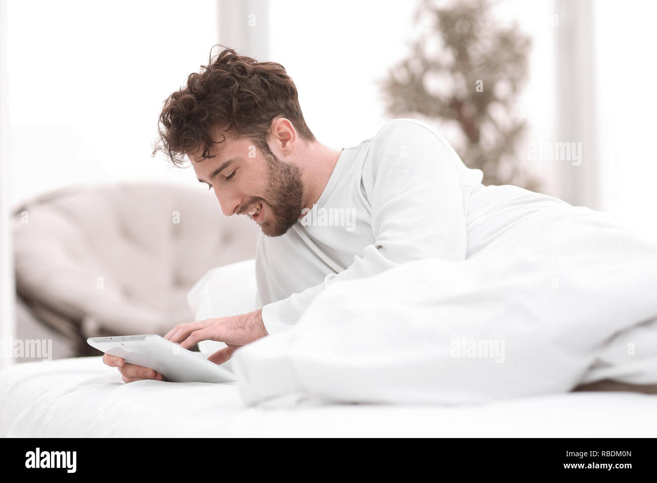 Man liegt auf dem Bett und Verwendung digitaler Tablet im Schlafzimmer Stockfoto