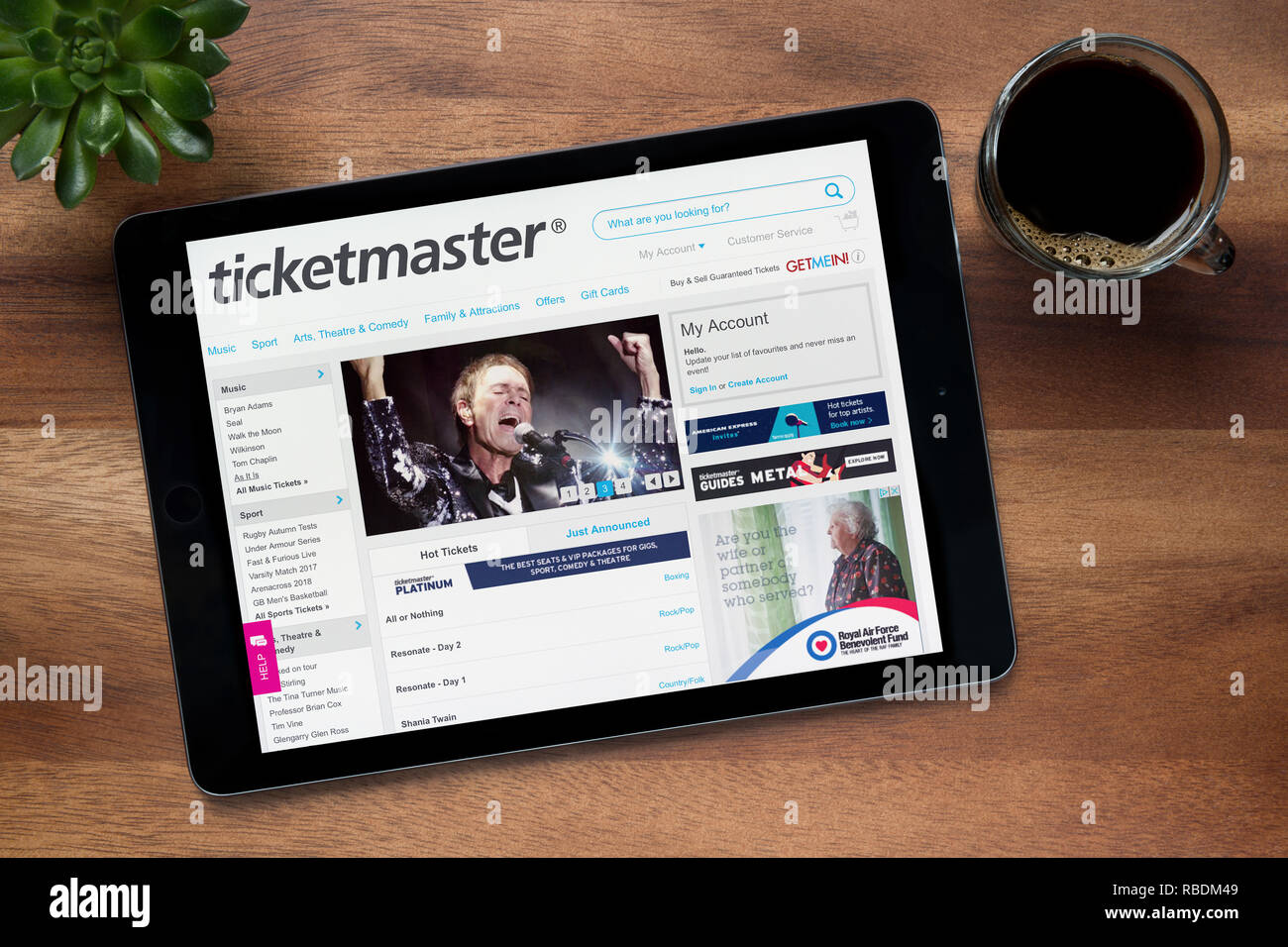 Die Website von Ticketmaster ist auf einem iPad Tablet gesehen, auf einer hölzernen Tisch zusammen mit einem Espresso und einem Haus Anlage (nur redaktionelle Nutzung). Stockfoto